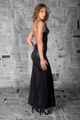 Vestido largo negro de tejido metalizado, con breteles finos y escote cruzado. Diseño entallado que se abre en una falda amplia con vuelo sutil.