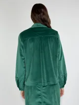 Chaqueta azul marino de terciopelo con cuello camisero, cierre frontal con botones, dos bolsillos de parche con solapa y mangas largas con puños abotonados.