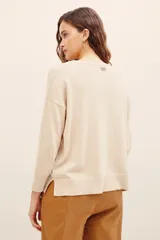Sweater color beige de punto suave, con cuello redondo, manga larga y diseño holgado. Presenta un delicado bordado de ramas y hojas con cuentas metalizadas en la parte superior derecha del pecho y el hombro.