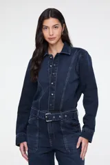 Enterito largo confeccionado en denim azul, con cuello camisero, cierre frontal con botones, mangas largas, cinturón incorporado con hebilla metálica, bolsillos aplicados en el pecho y bolsillos estilo cargo en los laterales de las piernas.