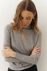 Rompeviento color beige con rayas horizontales finas en marrón, cuello alto y mangas largas.