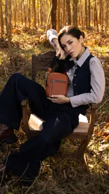 Bandolera morral color beige y blanco, con correa ajustable de tela en color blanco. Tiene cierre superior y un bolsillo frontal con cierre. Incluye un llavero decorativo.