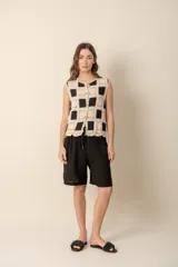 Chaleco de crochet con patrón de damero en color natural y negro, con botones al frente y sin mangas.