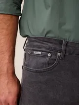 Pantalón de jean corte recto en color azul medio, con cierre de botón y cremallera, y bolsillos laterales y traseros.