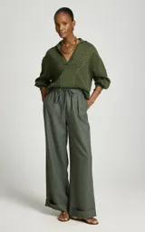 Sweater de punto color verde militar, con cuello polo y escote en V, mangas largas abullonadas con puños ajustados y tejido con tramas geométricas combinadas.