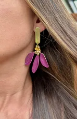 Caravanas colgantes con base rectangular metálica dorada y dije inferior compuesto por tres pétalos de color fucsia y pequeñas cuentas doradas.