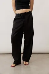 Pantalón de corte ancho y holgado, de color negro, con diseño estructurado y cinturón ajustable integrado en la cintura.