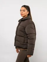 Campera puffer corta Umbro de color negro, con cuello alto, cierre frontal y bolsillos laterales. Presenta un diseño acolchado y logo de la marca bordado en el pecho.