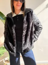 Campera con cuerpo de piel sintética tipo teddy y mangas acolchadas. Presenta cierre frontal, capucha y diseño de corte recto.