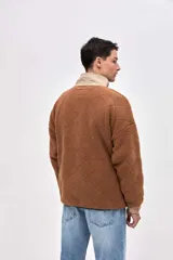 Buzo de sherpa con textura capitoneada, diseño de medio cierre y cuello alto en color beige contrastante. Presenta un calce holgado, mangas largas con puños elásticos y bolsillos laterales.