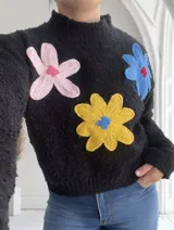 Sweater negro de cuello alto con apliques de flores tejidas en rosa, amarillo y azul.
