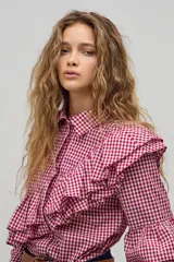 Camisa de manga larga con estampado de cuadros vichy en color rojo y blanco. Presenta cuello clásico, cierre frontal con botones de nácar y volados dobles decorativos en el frente, espalda y mangas.