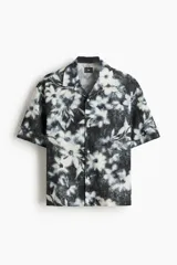 Camisa H&M de manga corta y corte relajado, con cuello abierto y estampado floreado en tonos negro y blanco.