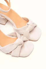 Sandalia de tacón cuadrado medio, confeccionada en terciopelo negro. Presenta un diseño de tiras cruzadas con nudo en la parte delantera y una tira ajustable con hebilla en el tobillo.