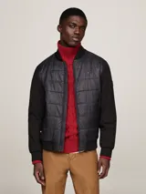 Campera bomber negra con frente acolchado y mangas de tejido liso. Cuello, puños y bajo de punto canalé. Cierre frontal con cremallera. Logo de Tommy Hilfiger bordado en el pecho.