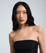 Blusa peplum sin tirantes de color negro, confeccionada en bengalina con diseño asimétrico en el dobladillo.