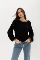 Buzo negro de punto en lanilla con diseño de ochos, corte holgado y escote redondo con flecos.