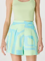 Short de tiro alto con diseño estampado geométrico en tonos verde y turquesa, cuenta con bolsillos laterales y cierre frontal.