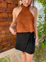 Top halter confeccionado en cuero color camel, con diseño sin mangas, espalda descubierta y ajuste mediante tiras.