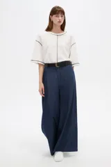 Pantalón de jean azul oscuro, tiro alto, corte ancho y holgado, con bolsillos y frunces en la cintura.