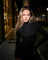 Vestido corto negro con cuello alto, mangas largas y lazo lateral.