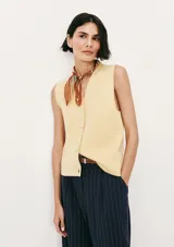 Chaleco de punto sin mangas en color amarillo suave, con cuello en V y cierre frontal de botones al tono. Presenta un diseño clásico y minimalista con un pequeño bordado decorativo en la parte inferior.