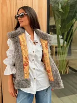 Chaleco de piel sintética en color gris, con diseño reversible. El interior presenta un forro de tela color mostaza con estampado floral bordado. Posee un corte holgado y sin mangas.