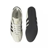 Championes Adidas modelo Tokyo, de diseño clásico y perfil bajo, confeccionados en cuero color blanco hueso con las icónicas tres tiras laterales y detalles en el talón en color negro. Presenta suela de goma negra y cordones al tono.