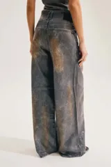 Jean de corte amplio en toda la pierna, con textura desgastada y efecto animal print de serpiente o cocodrilo en tonos gris y terracota.