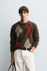 Jersey de punto con lana, corte relajado, cuello redondo y manga larga. Presenta un diseño de rombos en tonos marrón, beige y rojo con detalles bordados, y acabados en rib.