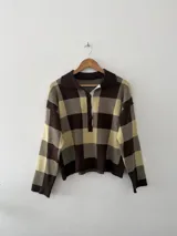 Sweater de tejido bremer con diseño a cuadros en tonos marrón y beige, cuello tipo polo y cierre frontal con botones.