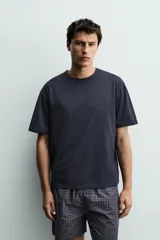 Set de pijama compuesto por una remera lisa de manga corta con cuello redondo y una bermuda a cuadros con bolsillos laterales y cintura elástica.