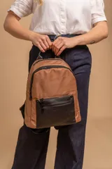 Mochila urbana de diseño combinado, confeccionada en tela resistente con bolsillo frontal y detalles en cuero sintético. Cuenta con compartimento principal con cierre y correas ajustables.