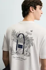 Camiseta de corte relajado, color blanco, con cuello redondo y manga corta. Presenta un pequeño estampado en el pecho con texto y un diseño gráfico más grande en la espalda.
