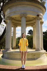 Camisa amarilla de inspiración oriental, confeccionada en algodón, con cuello mao y cierre frontal de nudos tradicionales. Presenta mangas tres cuartos abullonadas con puños elásticos y ribetes en contraste.