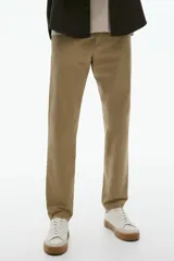 Pantalón de algodón color beige, estilo chino, con corte slim fit. Presenta cierre y botón frontal, bolsillos laterales al bies y bolsillos insertados con botón en la parte trasera.