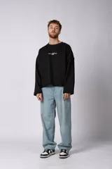 Buzo de cuello redondo confeccionado en tejido rústico con bordes al corte y costuras expuestas. Presenta un diseño boxy con estampado frontal y es reversible, permitiendo su uso por ambos lados.