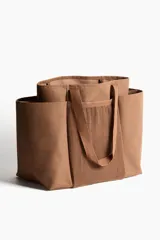 Cartera shopper grande en tejido grueso de mezcla de yute color marrón, con compartimento de malla en el frente y doble asa superior.