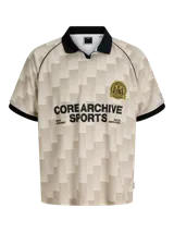 Camiseta tipo polo de manga corta con calce suelto. Presenta un diseño de cuadros en tonos beige y crema, con cuello y bordes de mangas en color negro. Incluye un escudo circular bordado en el pecho y estampado tipográfico en el frente.