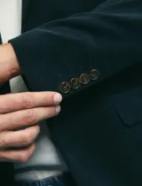 Saco sport de pana color marrón, con cuello de solapa, cierre frontal de dos botones, bolsillos laterales con tapa y puños con botones.