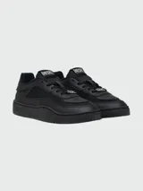 Zapatillas Diesel modelo S-Oval Skate de diseño urbano, color negro, confeccionadas en una combinación de cuero y tejido técnico. Presentan cierre de cordones, suela de goma robusta y detalle metálico con el logo de la marca en la parte frontal.