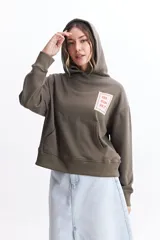 Canguro de felpa color verde militar, con capucha ajustable, bolsillos frontales tipo canguro y estampa en el frente y la espalda.