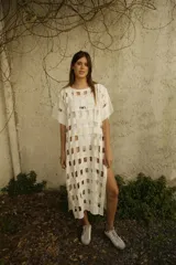 Vestido blanco de corte recto y largo midi, con diseño calado tipo rejilla y mangas cortas.