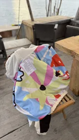 Campera de gabardina con diseño bicolor en tonos crudo y chocolate, con capucha forrada en polar. Presenta cierre frontal, mangas largas con puños elásticos y un parche distintivo en la manga.