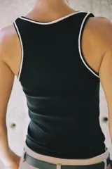 Musculosa de algodón color blanco con cuello redondo amplio y sisas. Cuenta con detalles de ribetes dorados brillantes en el escote, tirantes y costuras laterales.