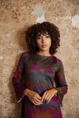 Vestido largo con estampado abstracto en tonos burdeos, verde y gris. Tiene mangas largas acampanadas y escote redondo.