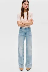 Jean de denim de algodón con tiro alto y pierna amplia de estilo wide leg. Presenta bolsillos tipo parche en la parte delantera y un lavado claro con efecto desgastado.
