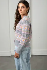 Cárdigan tejido de punto en color beige con diseño de flores y guardas caladas. Presenta escote en V, cierre frontal con botones y terminaciones acanaladas en puños y ruedo.