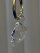 Aros tipo argolla de acero quirúrgico con dije colgante de cristal de Murano transparente con detalles en azul y una pequeña perla incrustada.