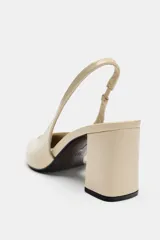 Zapato destalonado de piel en color beige, con punta fina, tacón ancho en bloque y tira trasera elástica.